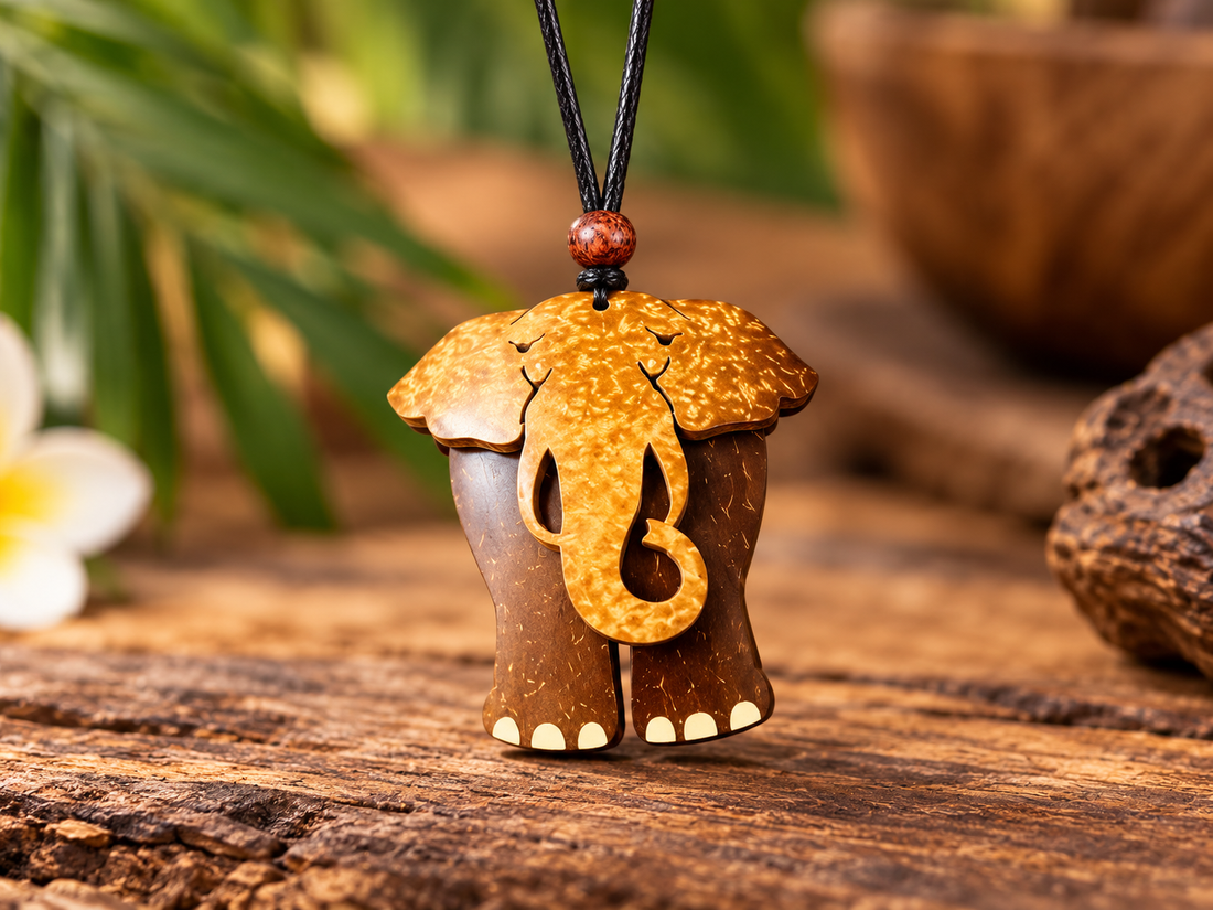 Elephant coconut shell pendant necklace on warm wooden surface with tropical greenery