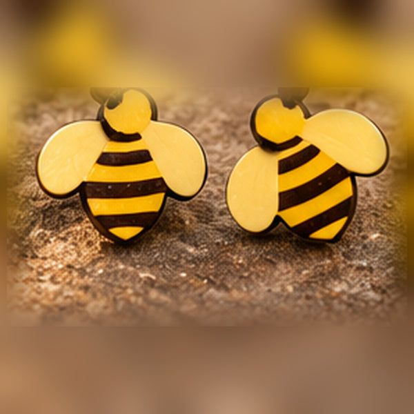 Pair of yellow honey bee stud earrings with dark stripes and wings on wood